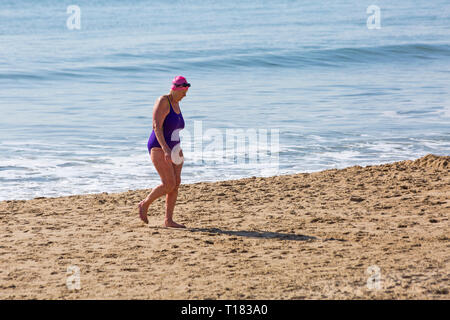 Bournemouth, Dorset, Großbritannien. 24. Mär 2019. UK Wetter: schöner sonniger Tag mit blauen Himmel und warmen Sonnenschein am Bournemouth Strände, die Besucher des Seaside Kopf Die meisten Wetter zu machen. Ältere Frau zu Fuß am Strand nach einem Bad im Meer. Credit: Carolyn Jenkins/Alamy leben Nachrichten Stockfoto
