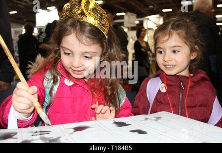 Peking, Frankreich. 15 Mär, 2019. Ein kleines Mädchen versucht, Chinesische Kalligraphie an der Chinesischen Ausstellungsbereich des 2019 Pariser Buchmesse in Paris, der Hauptstadt Frankreichs, am 15. März 2019. Credit: Yang Yimiao/Xinhua/Alamy leben Nachrichten Stockfoto