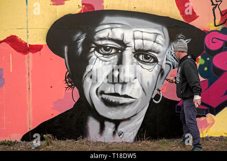 Graffiti Künstler arbeiten an einem Porträt von Keith Richards auf einer Wand in Leith, Edinburgh, Schottland, Großbritannien. Stockfoto