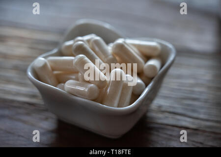 Vitimin Pillen angehäuft in einem kleinen Porzellan Schüssel Stockfoto