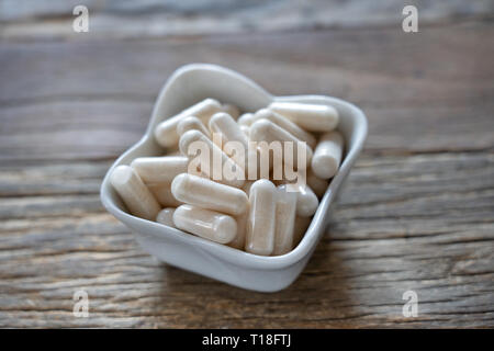 Vitimin Pillen angehäuft in einem kleinen Porzellan Schüssel Stockfoto