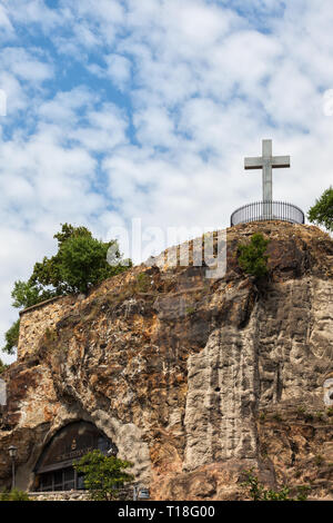 Höhle Kirche (Sziklatemplom) Eingang am Gellertberg mit steinernen Kreuz Denkmal in Budapest, Ungarn Stockfoto