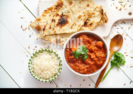 Frische und leckere Chicken Tikka Masala serviert in Keramik Schüssel. Indischen würzigen Gericht Curry. Mit Reis und Naan Brot auf den Seiten. Close Up. Flach. Stockfoto