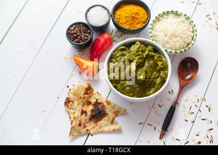 Traditionelle South Indian Korai Chicken Curry mit Minze und Koriander als Close-up in eine keramische Schüssel. Auf weissem Holztisch gelegt. Stockfoto