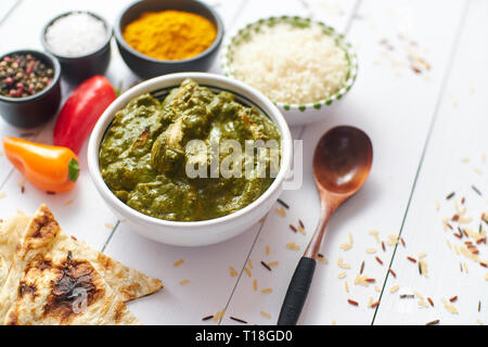 Traditionelle South Indian Korai Chicken Curry mit Minze und Koriander als Close-up in eine keramische Schüssel. Auf weissem Holztisch gelegt. Stockfoto