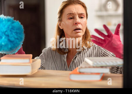 Dark-eyed Hausfrau tragen rosa Handschuhe Müdigkeit von Staub Stockfoto