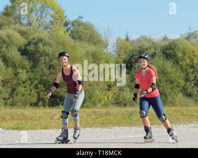 Zwei junge Frauen rollerblading im Spätsommer Stockfoto