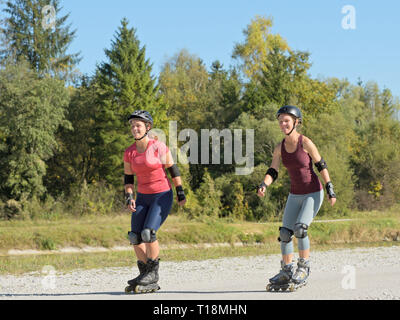 Zwei junge Frauen rollerblading im Spätsommer Stockfoto