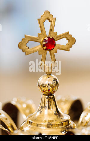 Goldene Hochzeit Kronen mit edlen Steinen liegen auf dem Tisch in der Kirche. Goldene Kreuz mit rotem Stein Stockfoto