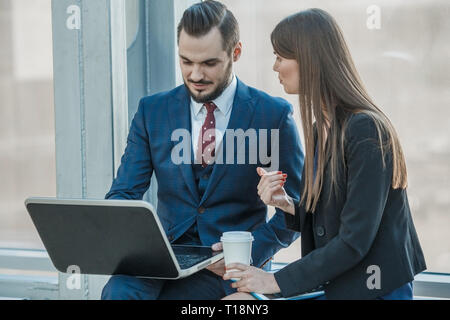 Freundliche Mitarbeiter im Büro über ihre Projekt am Laptop über Tasse Kaffee Stockfoto