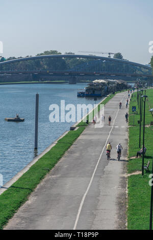 Krakau, Polen - 21. September 2019: Volk ist Wandern und Radfahren auf dem Radweg am Ufer der Weichsel, mit Kotlarski Brücke auf der Stockfoto