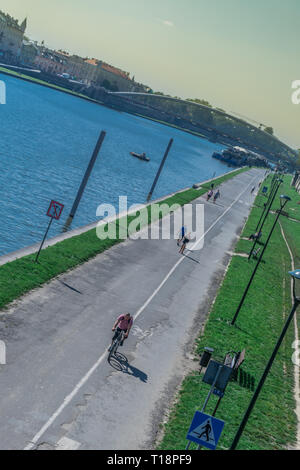 Krakau, Polen - 21. September 2019: Volk ist Wandern und Radfahren auf dem Radweg am Ufer der Weichsel, mit Kotlarski Brücke auf der Stockfoto