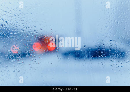 Verkehr Abstract in Regen. Verkehr von in einem Auto gesehen. Regentropfen auf der Windschutzscheibe und Auto Rückleuchten im Bokeh Stockfoto