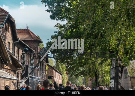 Oswiencim, Polen - 21. September 2019: Touristen, die über das Tor der nationalsozialistischen Konzentrationslager Auschwitz Stockfoto