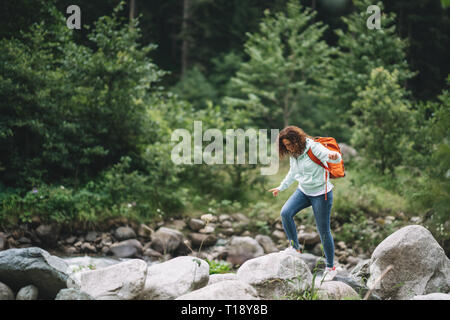 Schöne Frau Wanderer mit Rucksack in der Nähe von Wild Mountain River. Stockfoto