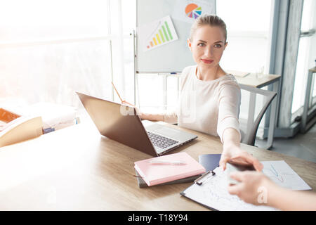 Ein Bild der Frau, die Ihr Telefon erhalten von Ihrer Helfer. Bereitet sie sich für Skype Konferenz Stockfoto