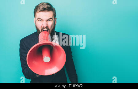 Ernsthafte Kerl ist schreiend und kreischend über die Lautsprecher. Er tut dies durch die Kamera gerade nach vorn schauen. Auf blauem Hintergrund isoliert Stockfoto