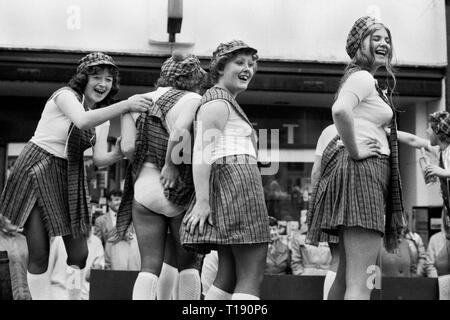 Insel Man, Peel Karneval 1970. Jugendlicher Mädchen von einem Schwimmer, der das ist, wird durch die Stadt gezogen. Mädchen, die ein wenig Spaß, hob ein anderes Mädchen Kleid, ihr Schottenrock, ihr Höschen. Alle lachen. 1978 HOMER SYKES Stockfoto