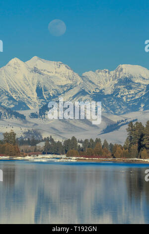 Mond über der flathead River und Mission Berge im Winter in der Nähe von Dixon, Montana Stockfoto