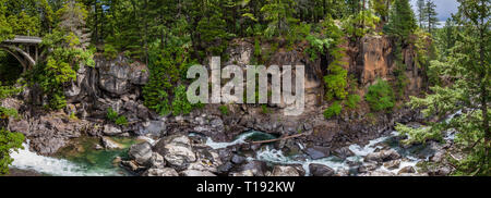 Panorama von einer Brücke auf der linken Seite mit einem Bach zwischen Felsbrocken in einem engen steilen Schlucht in einem dichten Wald in der Nähe der Rogue River in Oregon Stockfoto