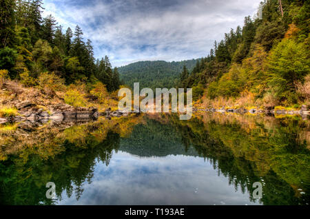 Orange und Gelb Herbst Farben reflektieren in der Rogue River auf einer ruhigen Abschnitt am Nachmittag Stockfoto