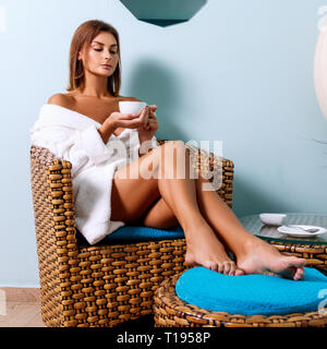 Frau im Bademantel Tee trinken in Spa Salon. Stockfoto