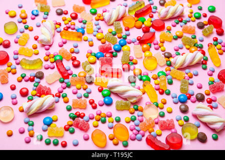 Geburtstag Konzept. Bunt gemischte süsse bonbons auf Pastell rosa Hintergrund, Detailansicht Stockfoto