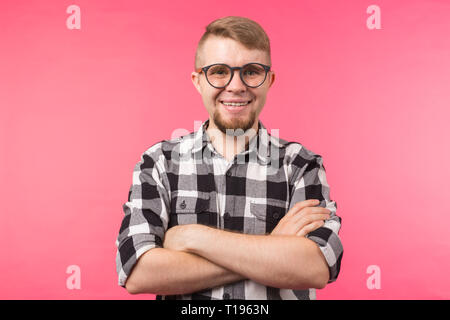 Porträt eines lächelnden bärtigen Mann in Brillen an Kamera über rosa Hintergrund suchen Stockfoto