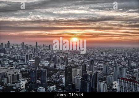 Dieses einzigartige Foto zeigt den spektakulären Sonnenuntergang in Bangkok, Thailand. Sie können sehen, wie sich die Stadt in der Abendsonne leuchtet mit einer großen Wolke Stockfoto