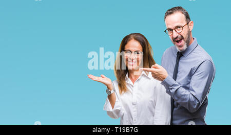 Mittleres Alter spanischer verliebtes Paar Brillen über isolierte Hintergrund erstaunt und lächelt in die Kamera während der Präsentation und mit der Hand nach w Stockfoto