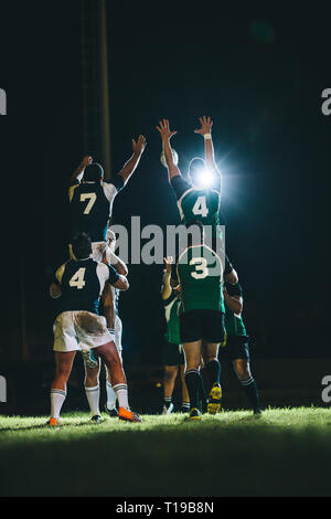 rugby-Spieler, die im Stadion um eine Linie springen. Teams, die während des Rugby-Spiels um den Ballbesitz springen. Stockfoto