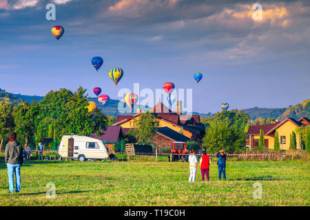 Atemberaubende bunte Heißluftballons bei Sonnenaufgang. Touristisches Dorf und Camping Platz mit Touristen an der bunten Heißluftballons betrachten, Sovata Stockfoto