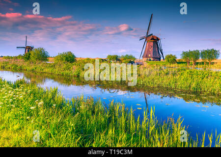 Fantastische Reise Ort, Wasser Kanal in Kinderdijk mit traditionellen alten holländischen Windmühlen bei Sonnenuntergang, UNESCO-Weltkulturerbe, Niederlande, Europa Stockfoto