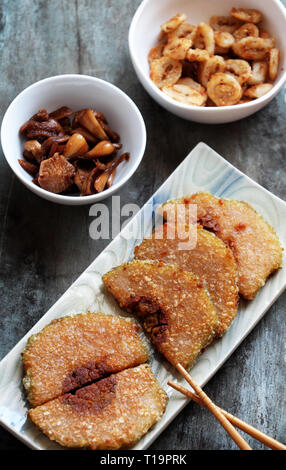 Traditionelle vietnamesische Essen auf tet, geschnitten von glutenhaltigen Reis Kuchen gebraten auf Platte mit auf die Platte gebeizt, Foto von oben Blick auf Holz- Hintergrund Stockfoto