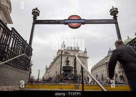 Mann verlässt die U-Bahnstation der Piccadilly Circus, die Schritte, während Touristen und Einheimische, die das Londoner oben sitzen die Schritte des Denkmals. Stockfoto