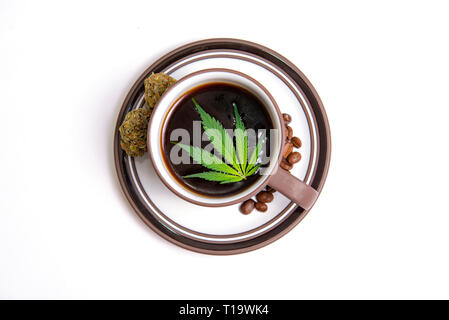 Detail von Cannabis Kaffee Tasse mit Marihuana Blätter und Kaffeebohnen isoliert über Weiß, Marihuana edibles Konzept Stockfoto