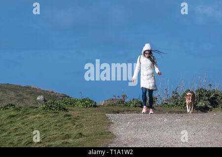 Eine Frau, die zu ihrem Hund an einem windigen Tag. Stockfoto