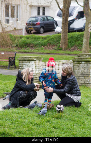 Ein Kind füttern Tauben und Enten mit seiner Mutter und Großmutter in einem Park. Stockfoto