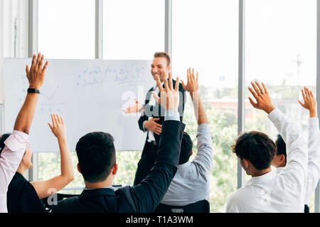 Viele Geschäft Leute die Teilnehmer heben ihre Hand in Business Seminar Konferenz Event Inside corporate Unternehmen Office mit Lautsprecher vorne Stockfoto