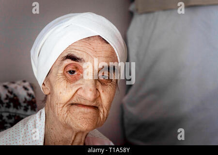 Portrait eines älteren türkischen Frau mit traditionellen Motorhaube im Zimmer sitzen. Stockfoto