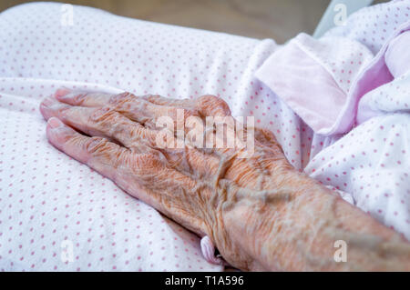 Hand der Hand eine ältere Frau Schlafanzüge tragen. Alterungsprozess. Stockfoto