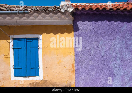 Orange und lila Wand mediterrane Haus mit blauen Holz- Fenster. Aus farbigen Wänden außerhalb Hintergrund, während sonniger Tag. Stockfoto