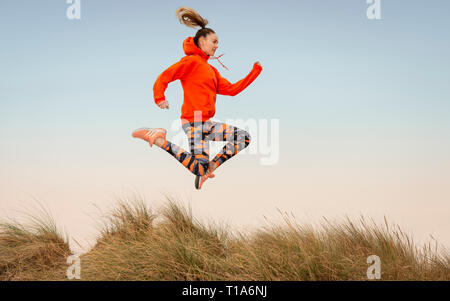 Frau draußen laufen, springen in die Luft. Stockfoto