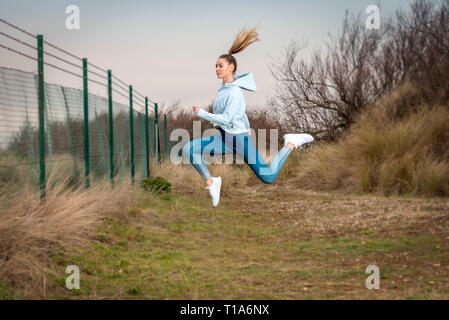 Frau draußen laufen, springen in die Luft. Stockfoto