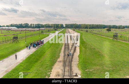 Oswiencim, Polen - 21. September 2019: Gruppen von Touristen zu Fuß entlang der Bahnlinie, wo der Wagen mit der Birkenau Gefangenen angekommen. Stockfoto
