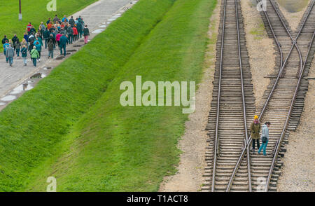 Oswiencim, Polen - 21. September 2019: Gruppen von Touristen zu Fuß entlang der Bahnlinie, wo der Wagen mit der Birkenau Gefangenen angekommen. Stockfoto