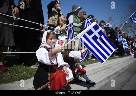 Thessaloniki, Griechenland. 25 Mär, 2019. Kinder gekleidet in traditionellen Kostümen halten Griechischen Fahnen, wie sie eine Parade beobachten. Die nationalen Feiertag von 25. März markiert den Beginn der griechischen Revolution zurück in 1821, die für die Unabhängigkeit gegen die 400-jährige Osmanische Herrschaft geführt. Während der Parade Hunderte von Menschen protestierten gegen Prespa Vereinbarung riefen Slogans wie ''Mazedonien ist nur einer, und es ist die Griechische''. Prespa Vereinbarung ist eine Vereinbarung am 12. Juni 2018 erreicht zwischen Griechenland und Mazedonien, unter Schirmherrschaft der Vereinten Nationen, bei der Lösung eines langjährigen Streit über dessen Nam Stockfoto