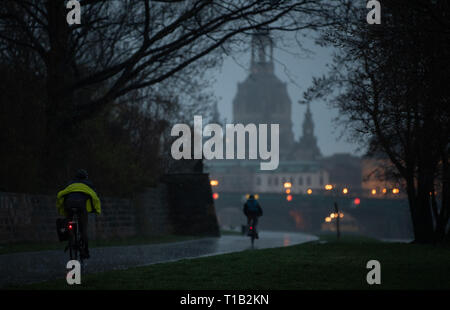 Dresden, Deutschland. 25 Mär, 2019. Radfahrer fahren im Regen entlang der Elbe Radweg vor der historischen Kulisse der Altstadt mit der Frauenkirche. Credit: Robert Michael/dpa-Zentralbild/ZB/dpa/Alamy leben Nachrichten Stockfoto