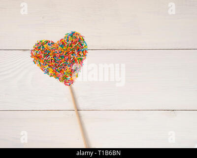 Candy besprüht Form Herz Form. Bunte Herz-Form von candy Konfetti auf weißem Holz- Hintergrund. Valentines Tag Konzept. Top View oder flach mit Copyspace. Stockfoto