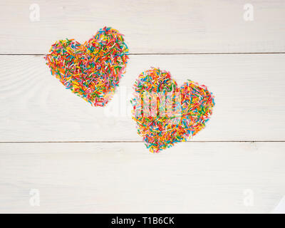 Candy besprüht Form Herz Form. Bunte Herz-Form von candy Konfetti auf weißem Holz- Hintergrund. Valentines Tag Konzept. Top View oder flach mit Copyspace. Stockfoto